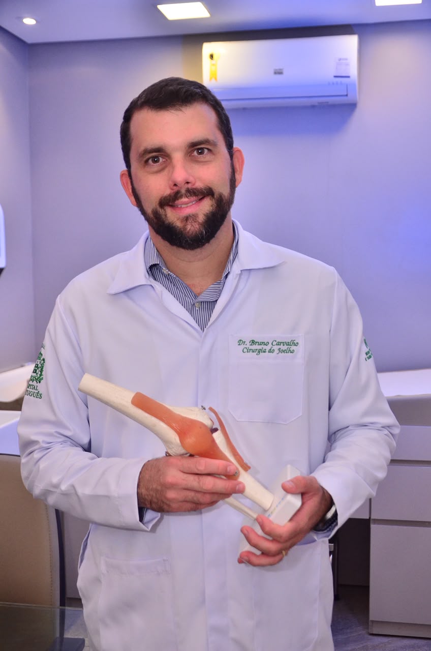 Dr. Bruno Carvalho com modelo anatômico do joelho